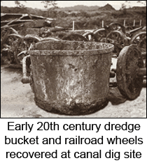 Early 20th century dredge bucket and railroad wheels covered at canal dig site