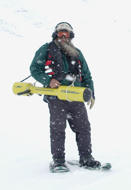A man holding a Diver Held Magnetometer while snowing